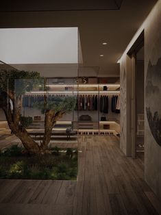 a room that has a tree in the center and clothes on racks behind it, along with wooden flooring