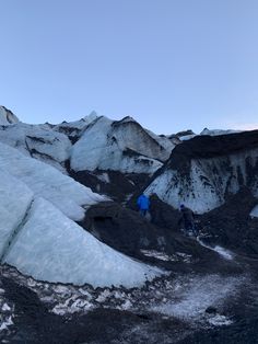 two people hiking up the side of a mountain covered in snow and icebergs