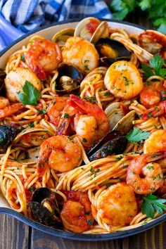 pasta with shrimp, mussels and clams in a skillet on a wooden table