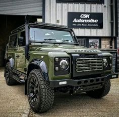 a green land rover is parked in front of a building