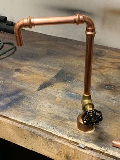 an old fashioned copper faucet on top of a wooden table next to a power cord