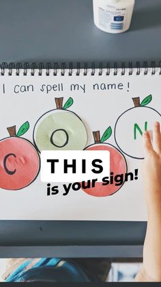 a child's hand is pointing at a sign that says, i can spell my name