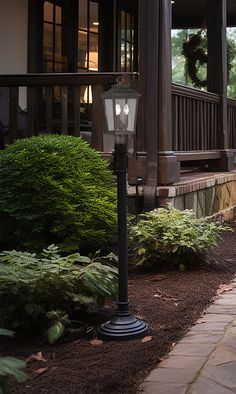 a lamp post sitting on the side of a walkway next to a building with a porch