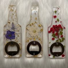 three bottle openers decorated with flowers and gold flakes