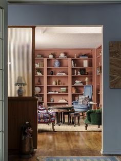 a living room filled with furniture and bookshelves next to a doorway leading into a dining room