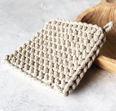 a crocheted dishcloth sitting on top of a wooden plate next to a bowl