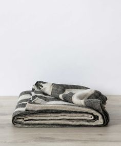 two blankets folded on top of each other in front of a white wall and wooden floor