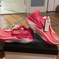 a pair of pink nike shoes sitting on top of a box