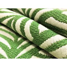 the green and white fabric is folded in two rows, with an intricate pattern on it