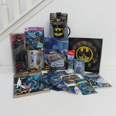 the batman movie memorabilia is on display in front of a stair case, clock and other collectibles