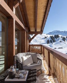 the balcony is covered with snow and has two chairs, a coffee table, and an ottoman