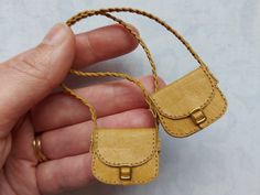 a hand holding a small leather purse with two rings on it's sides and a string attached to the clasp