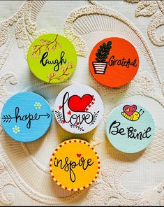 four badges with different designs on them sitting on a lace doily covered tablecloth