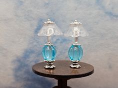 two glass lamps sitting on top of a wooden table