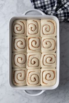 cinnamon rolls in a white baking dish on a marble counter