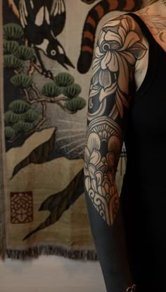 a woman with tattoos standing in front of a wall hanging on it's side