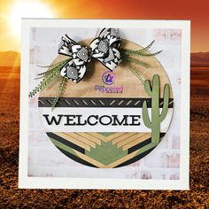 a welcome sign in the desert with a cactus and bow on it's head