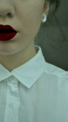 a close up of a woman with red lipstick on her lips and white collared shirt