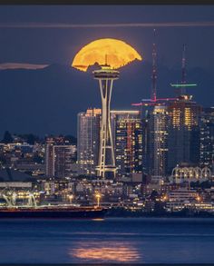 the moon rises behind the space needle in seattle