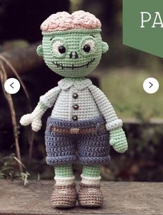 a crocheted zombie doll is standing on a rock in front of some trees