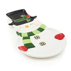 a white plate with a green and red snowman on it's face, wearing a black hat