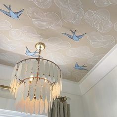 a chandelier hanging from a ceiling with birds painted on the ceiling above it