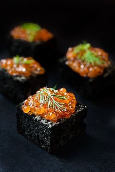 small pieces of black bread topped with red cavia and sprig of rosemary