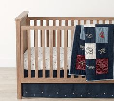 a baby crib with a quilted blanket on it's side and the bedding is made from wood