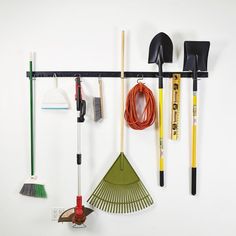 there are many different tools hanging on the wall with it's hooks and brooms