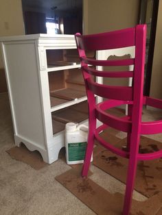 a pink chair sitting next to a white bookcase on top of a carpeted floor