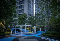 an empty playground in the middle of a city at night with buildings in the background