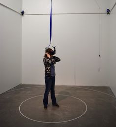 a woman standing in an empty room while talking on her cell phone with a blue ribbon hanging from the ceiling