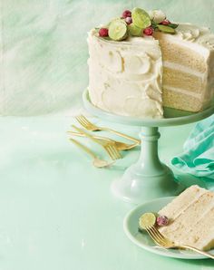 a cake with white frosting and fruit on top sitting on a plate next to a fork