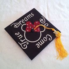 a black graduation cap with mickey mouse ears and beads on it that says dreams come true