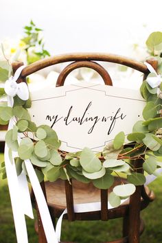 a sign that says my wedding life is on top of a chair with greenery around it