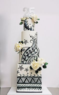 a three tiered cake with white flowers on top is decorated in black and white