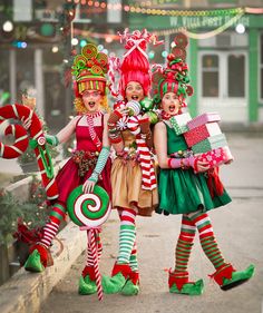 three women dressed in christmas costumes holding candy canes