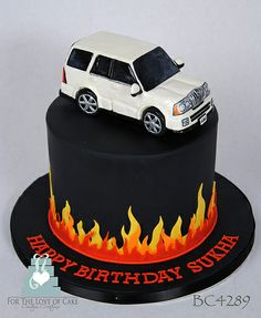 a birthday cake with a white car on top and flames in the middle, sitting on a black plate