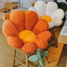 an orange and white flower shaped chair sitting on top of a wooden floor next to a plant