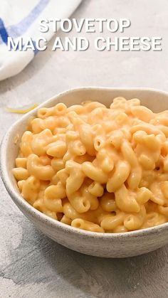 a bowl filled with macaroni and cheese sitting on top of a table next to a fork