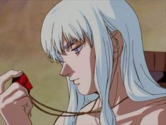 an anime character with long white hair and blue eyes holding a red object in her hand