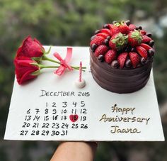 a chocolate cake with strawberries on top and a red rose sitting next to it