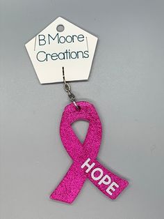 a pink ribbon with the words hope hanging from it's hook on a gray background