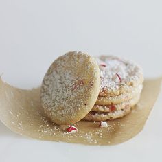 three cookies with powdered sugar on top are sitting on a piece of parchment paper