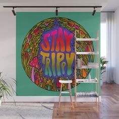 a wall mural with the words stay trip painted on it in bright colors and surrounded by plants