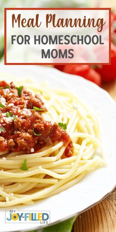 a white plate topped with spaghetti and meat on top of a wooden table next to tomatoes