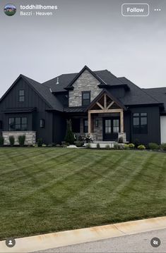 a large black house with lots of windows and grass in front of it on a cloudy day