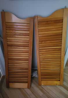 two wooden slatted doors sitting next to each other on a hard wood floor