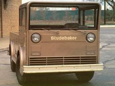 an old truck is parked on the side of the road in front of a brick building