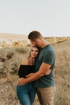 a man and woman hugging in the middle of a field